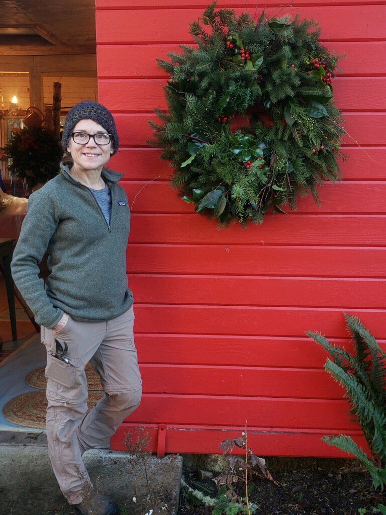 Woman standing beside holiday wreath on red wall